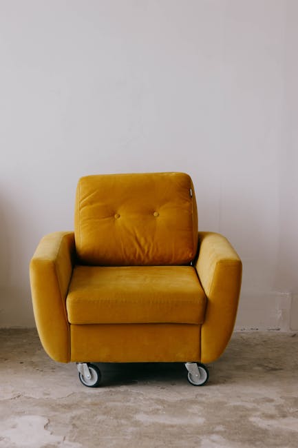A white upholstered sofa with tufted backrests and rolled arms is positioned against a white wall with decorative paneling in a well-lit living room. The sofa’s fabric appears clean and well-maintai